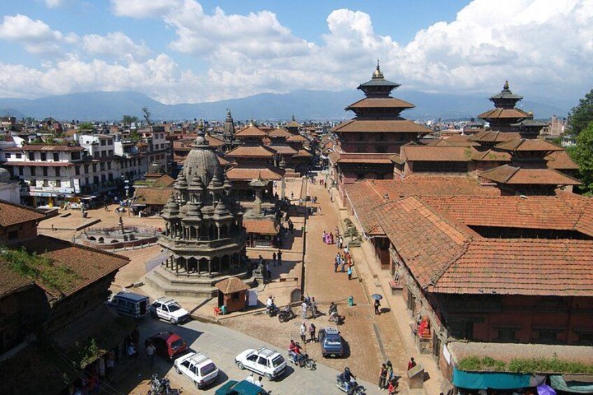 A traditional cityscape with tiered pagoda-style buildings, a central temple, and a bustling street with vehicles and pedestrians. 4
