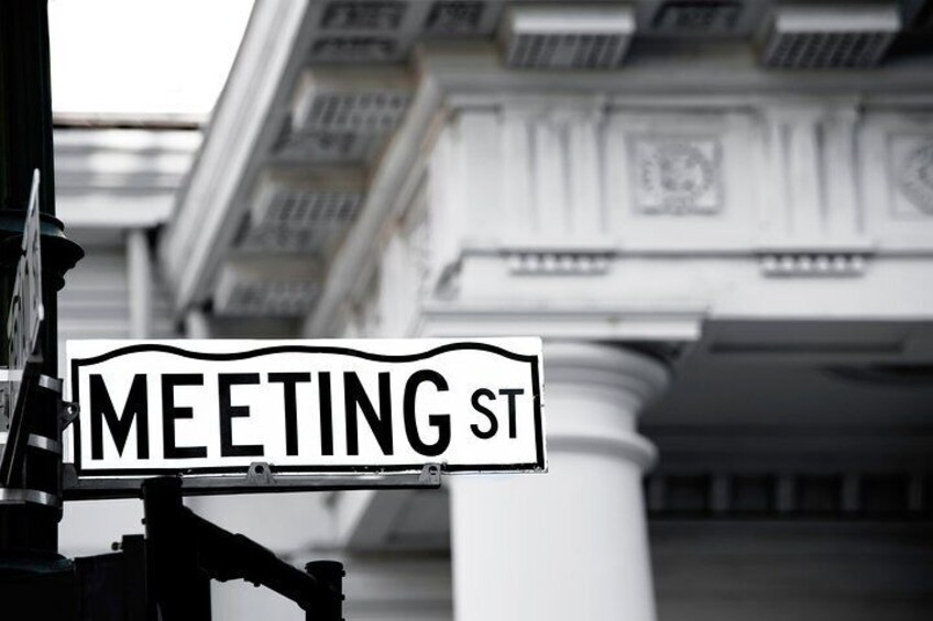 Een straatnaambordje met de tekst 'MEETING ST' voor een klassiek gebouw met kolommen. 5
