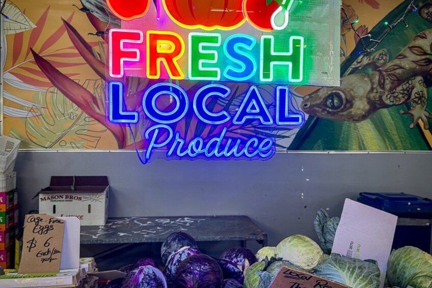 A neon sign advertising 'FRESH LOCAL Produce' with various vegetables in front. 5