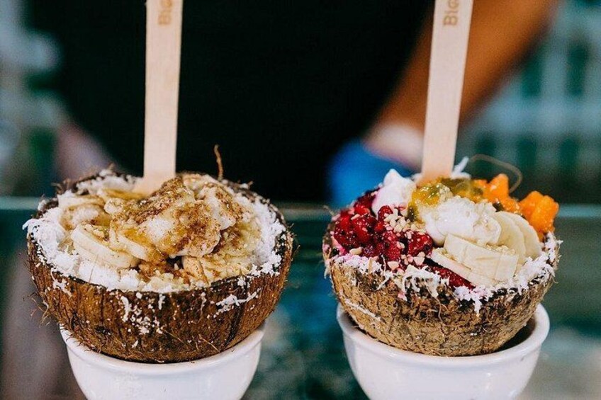 Twee schaaltjes toetjes met toppings, elk met een houten stokje. 1