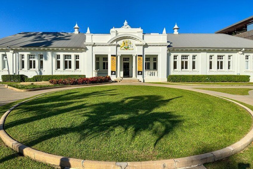 A white building with a central entrance, surrounded by a well-maintained lawn and a curved pathway. 2