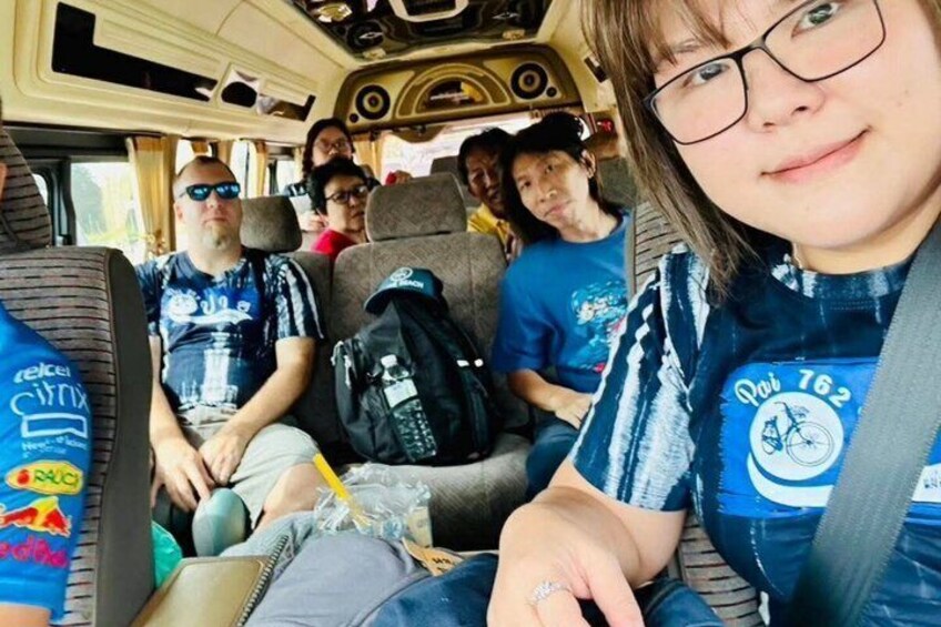 A bus interior with passengers wearing matching blue shirts with a logo and text. 5