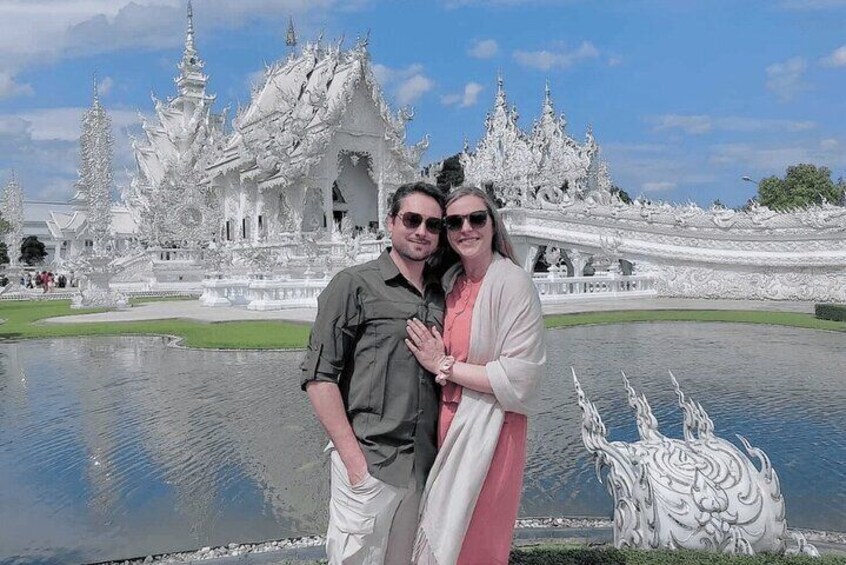 A couple standing in front of a white ornate temple with a reflective pond. 1