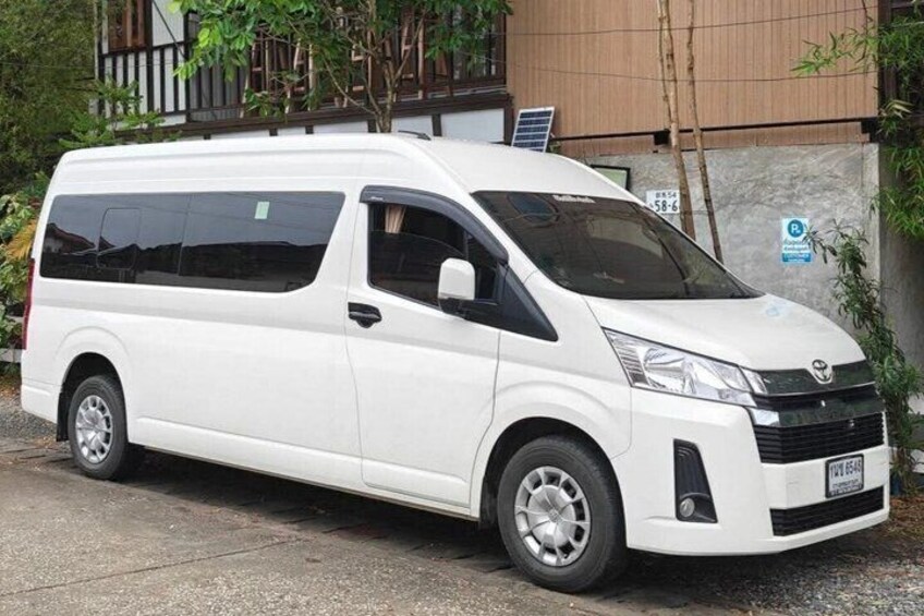 A white van parked on a concrete surface with a building in the background. 3