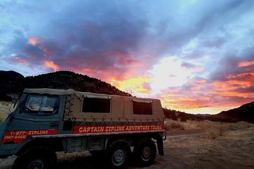 A truck with a canvas cover parked on a dirt road. 2