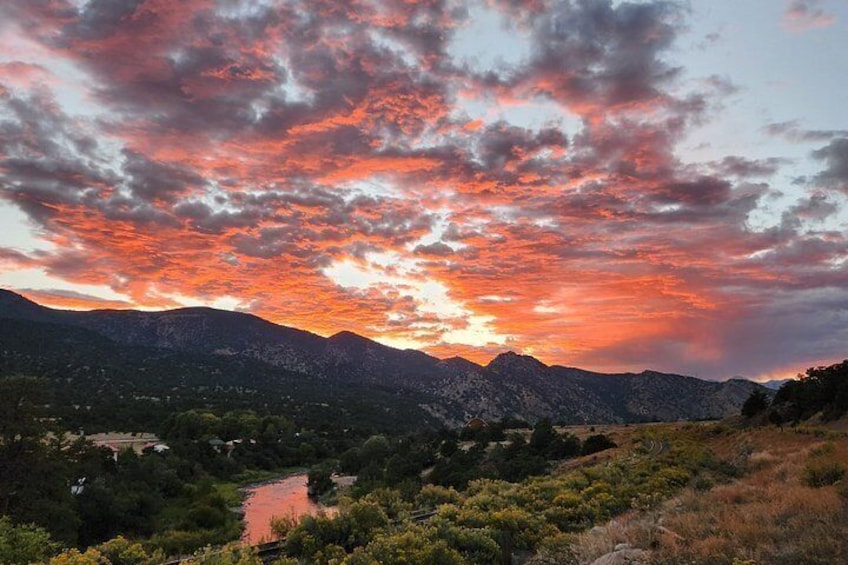 A sunset over a mountainous landscape with a river and greenery. 5