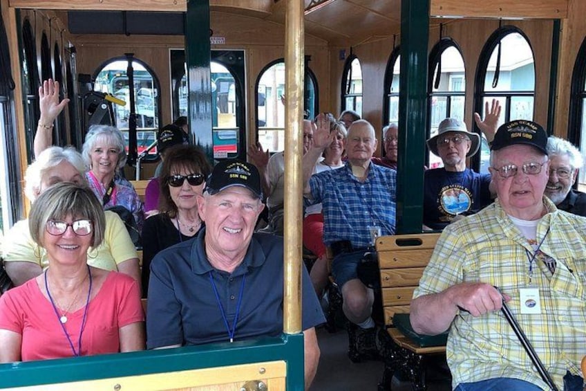 A group of people on a wooden tram with arched windows. 2