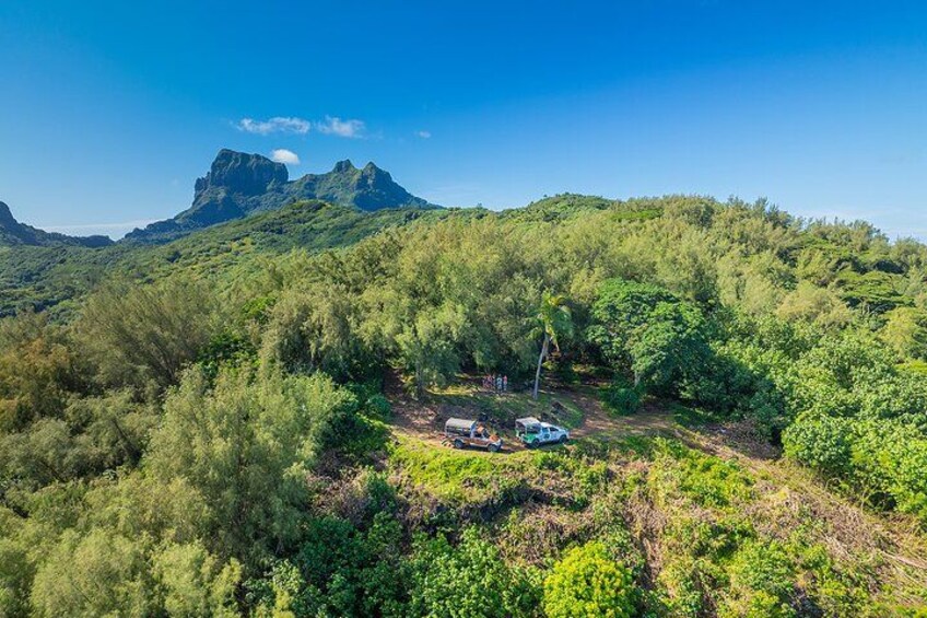 Un paysage montagneux, caractérisé par une végétation luxuriante et verdoyante, et un petit véhicule stationné sur un chemin de terre. 1
