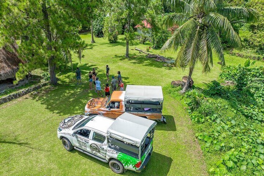 Un véhicule blanc, équipé d’une remorque aménagée en camping-car, est garé sur une pelouse, avec des arbres et un palmier en arrière-plan. 4