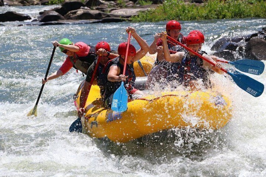 Un groupe de personnes à bord d’un radeau jaune naviguant sur une rivière à courant rapide. 1