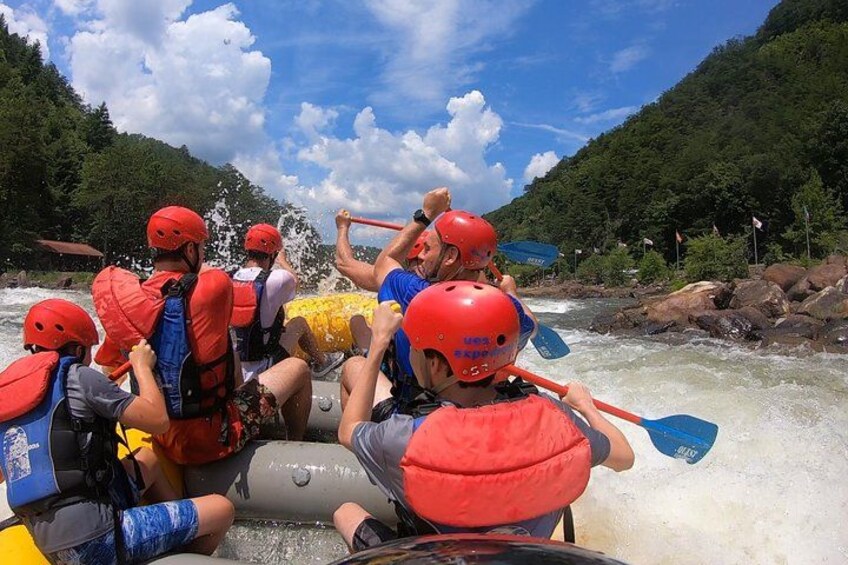 A group of people rafting on a river surrounded by greenery. 2
