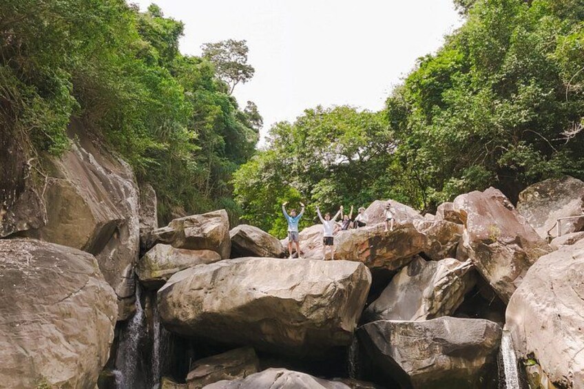 A waterfall cascading over large rocks with people standing on them. 4