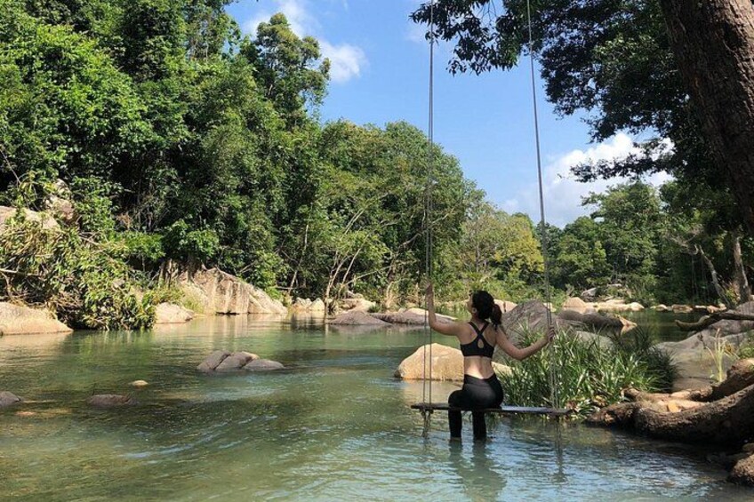 A person swinging on a rope over a river surrounded by trees. 5