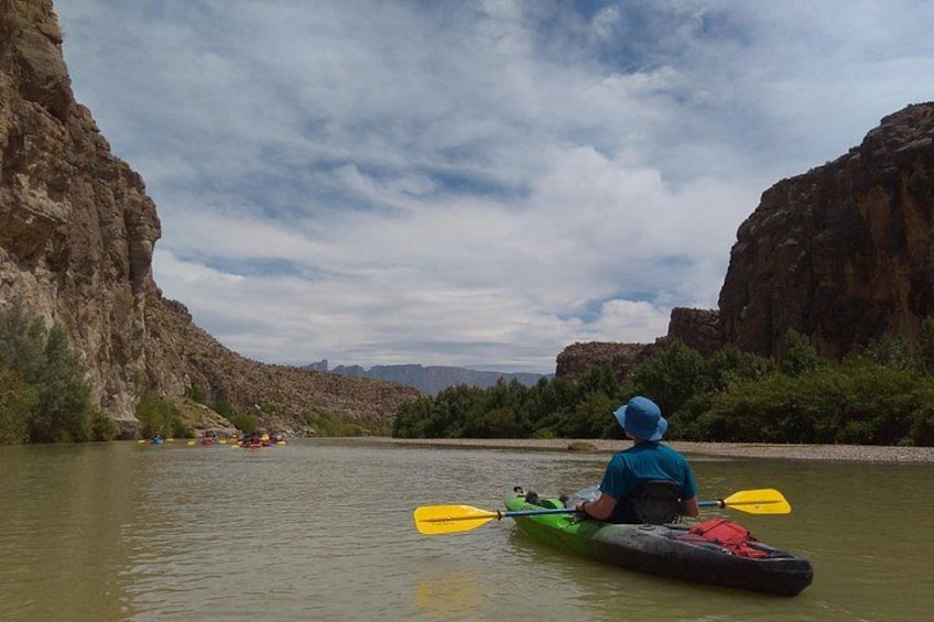 A person kayaking on a river with rocky cliffs on either side. 3