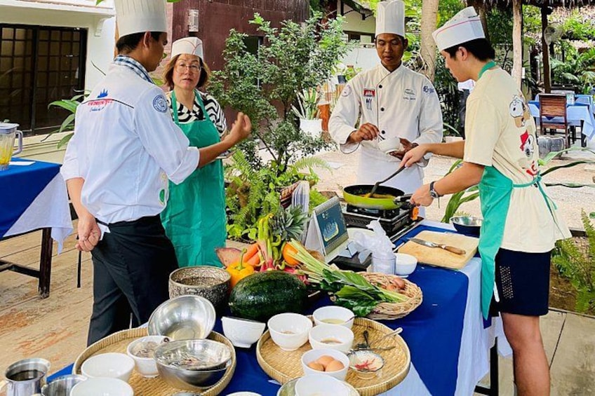 Koks bereiden eten buiten, aan een tafel vol ingrediënten en kookgerei. 1