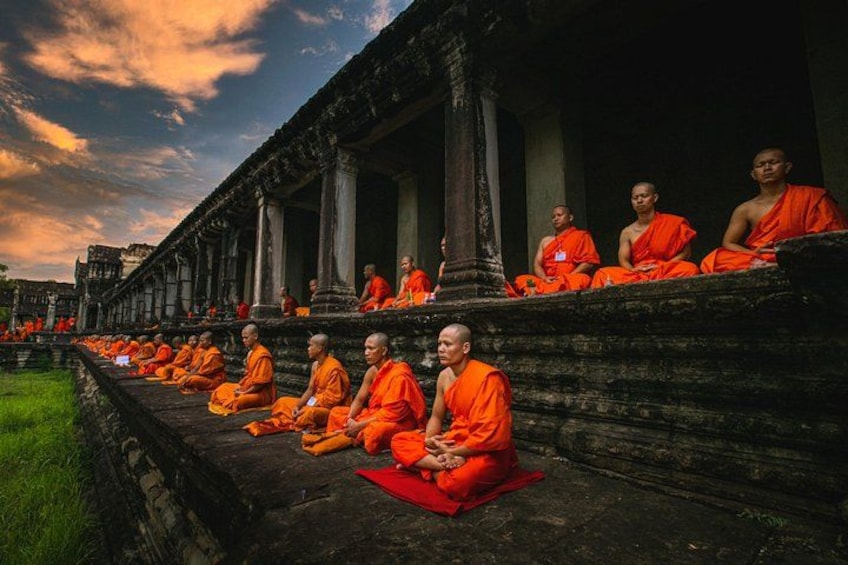 Monks in orange robes seated on steps of a temple. 5