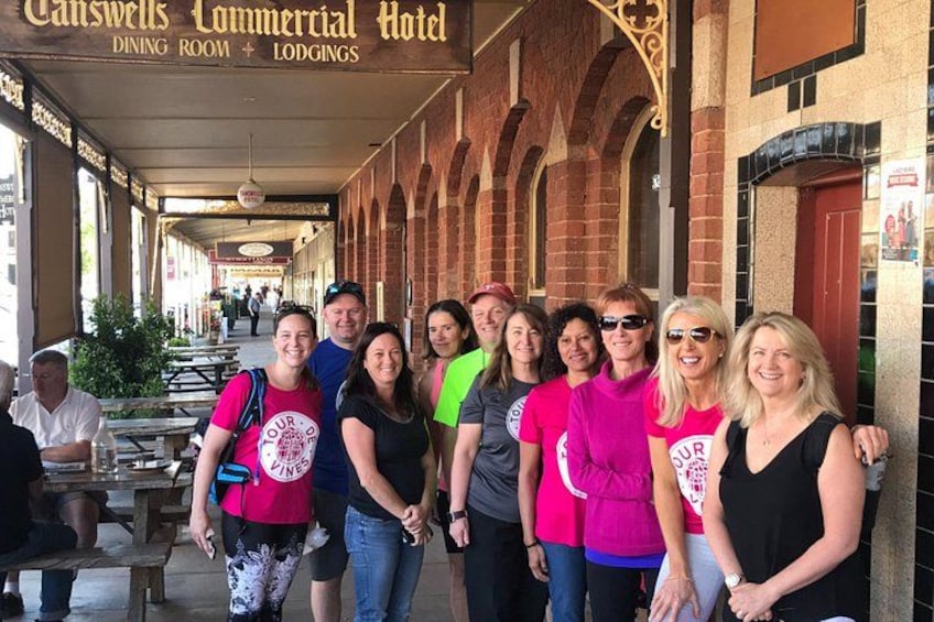 A group of people standing in front of Canswells Commercial Hotel, which has a covered dining area and lodging facilities. 2