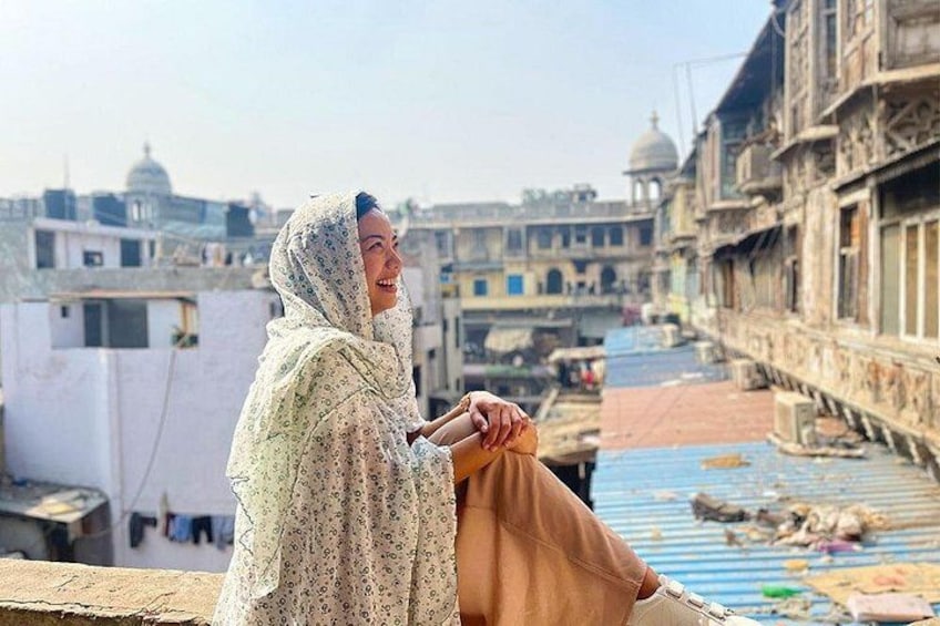 A person sitting on a rooftop overlooking a densely built urban area with historical architecture. 4