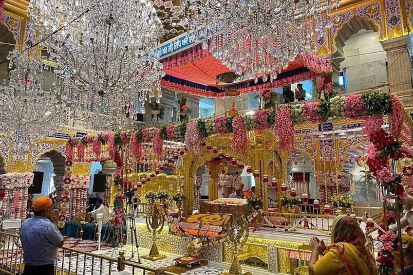 A temple interior with ornate decorations, a central altar, and a person performing a ritual. 2