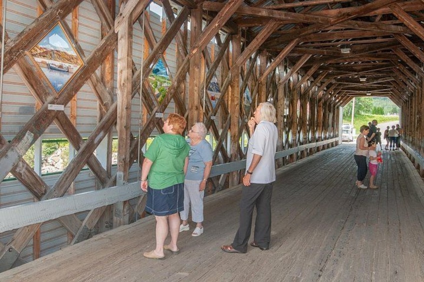 A covered wooden bridge with people walking on it. 3