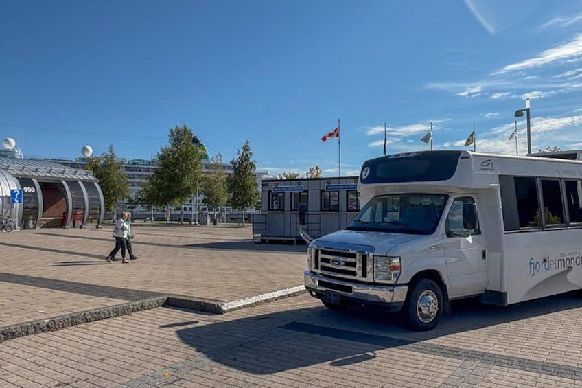 A white bus parked on a paved area with a building in the background. 4