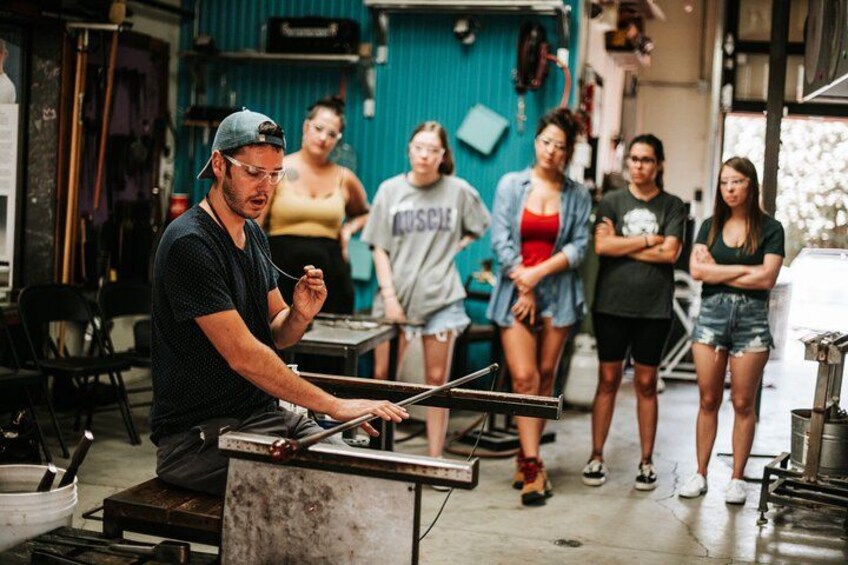 A person working on a metal structure in a workshop with several people standing around. 2