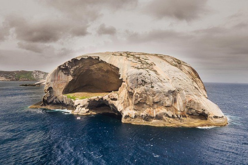 A large rock formation with a cave-like opening surrounded by water. 4