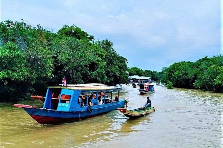 Un río con barcos, follaje verde denso y un cielo nublado. 2