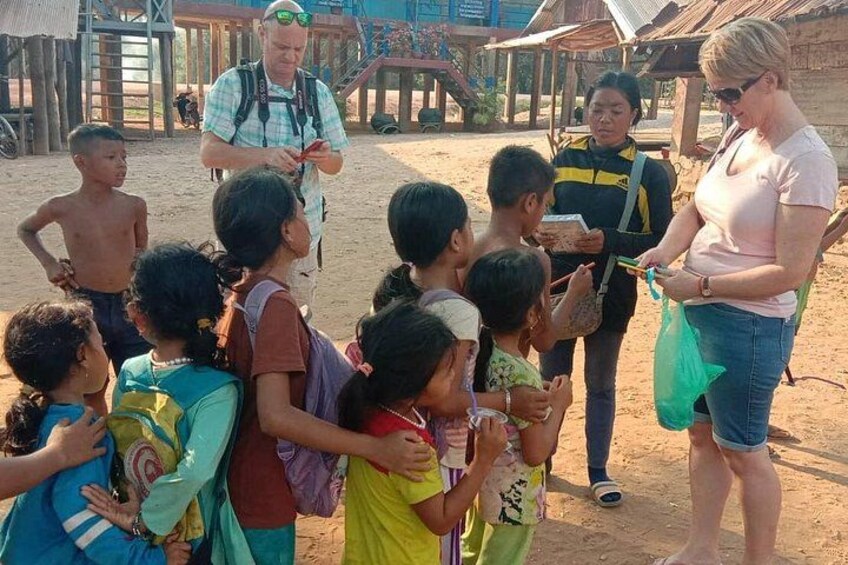 Een groep kinderen en volwassenen is buiten samen, sommigen houden boeken vast, met een man op de achtergrond met een rugzak. 4