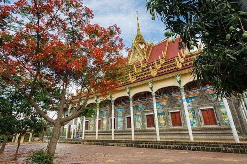 A traditional temple with a golden spire, red and blue decorations, and a tree with red leaves in the foreground. 4