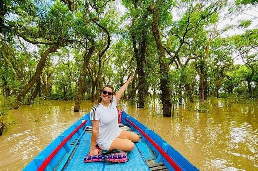 A person in a boat on a river surrounded by trees. 1