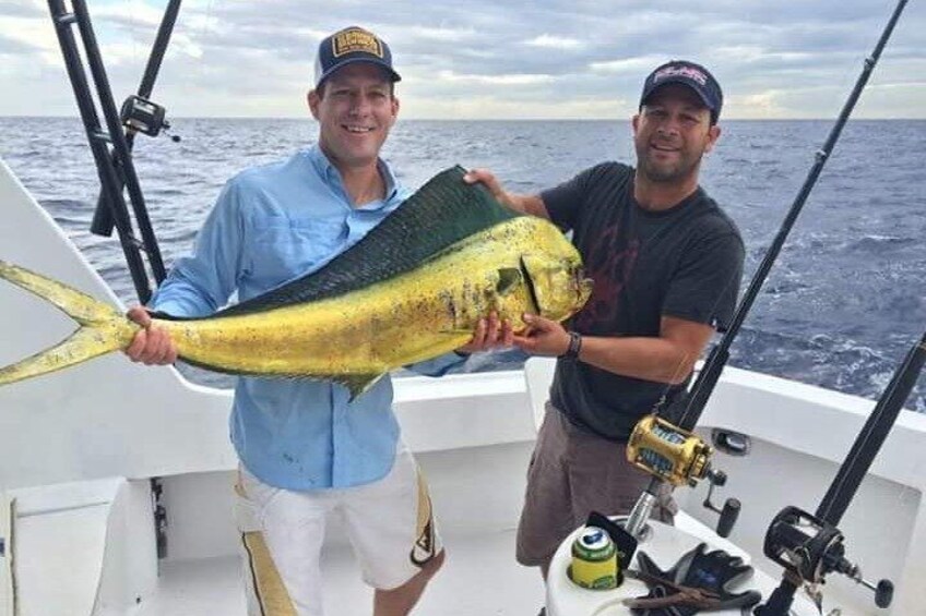 Two people on a boat holding a large fish. 4