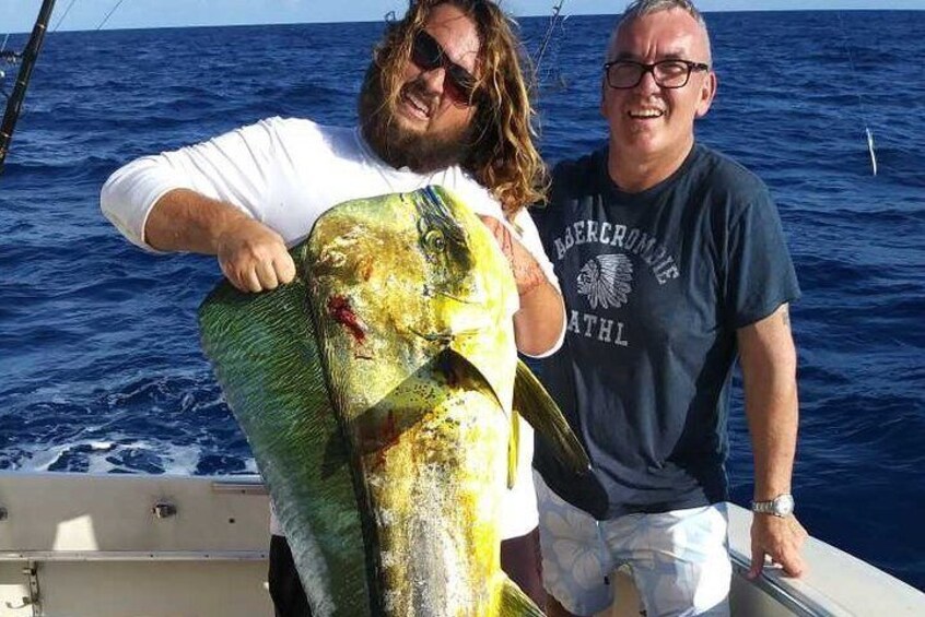 Two people on a boat holding a large fish. 5