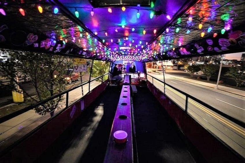A covered walkway with colorful lights and a row of benches. 1