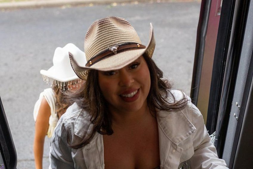 A person wearing a white hat and a denim jacket stepping out of a vehicle. 3