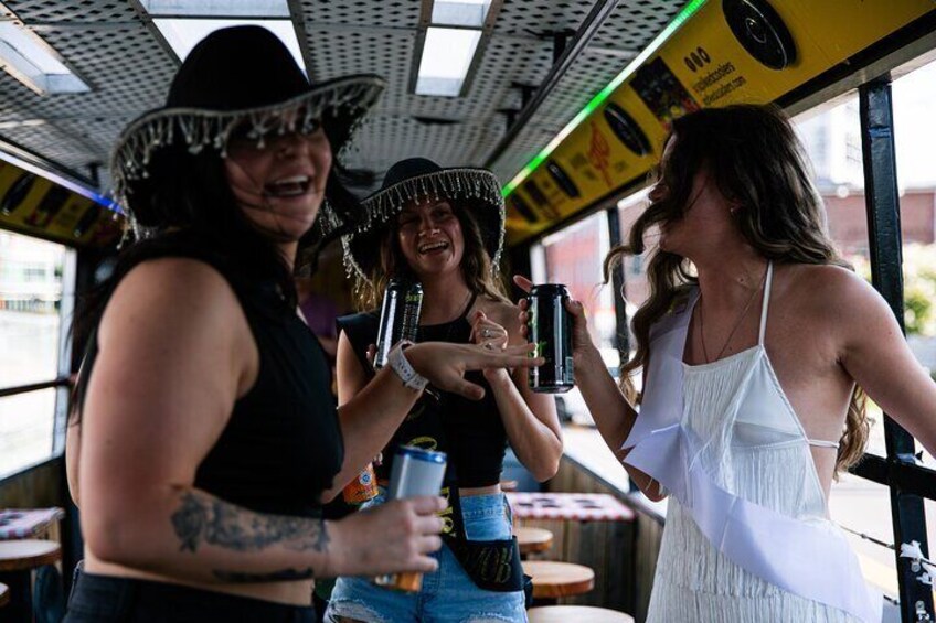 Three people wearing sombreros, holding drinks, and standing in a vehicle with a yellow interior. 2