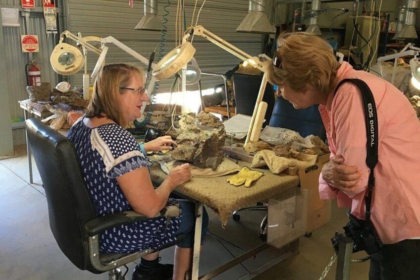 Zwei Personen arbeiten an einem Tisch mit Werkzeugen und Materialien, möglicherweise in einer Werkstatt oder einem Labor. 2