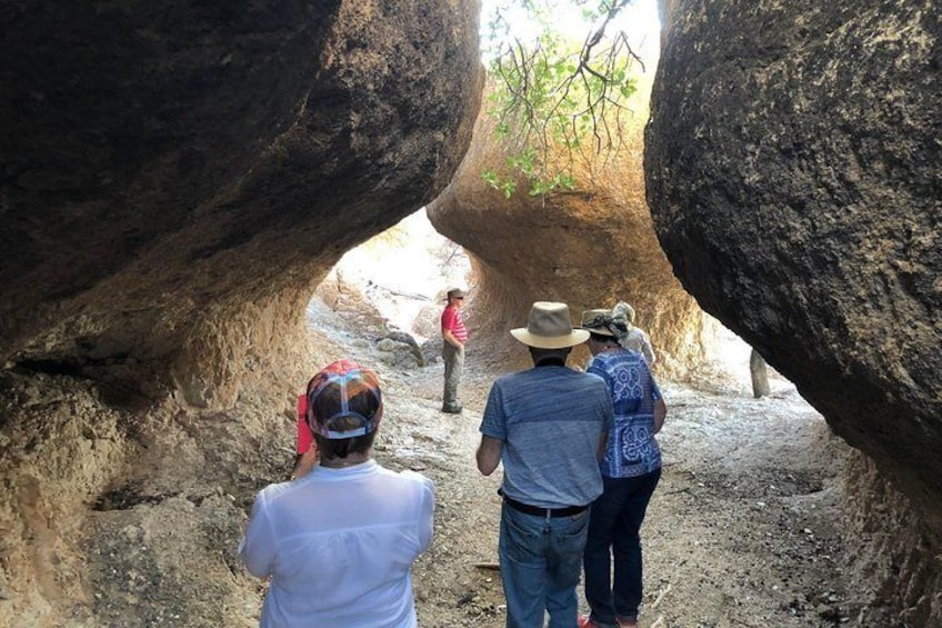 A group of people walking through a narrow canyon with large rock formations on either side. 5