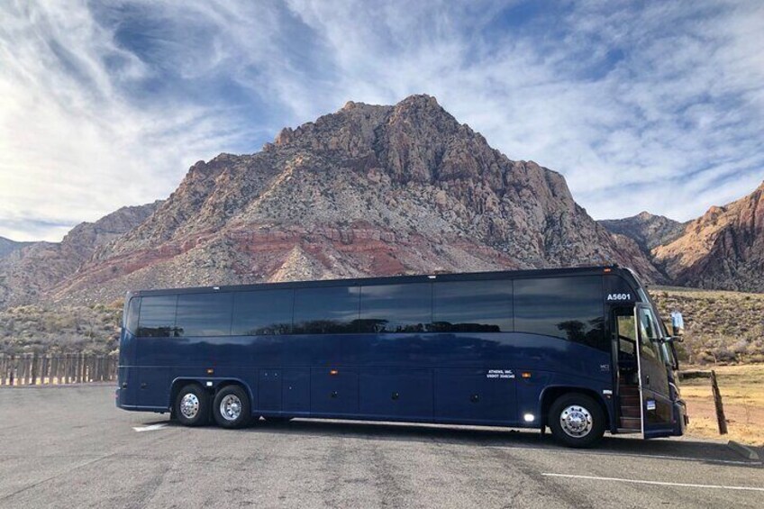 A blue bus parked on a road with mountains in the background. 4