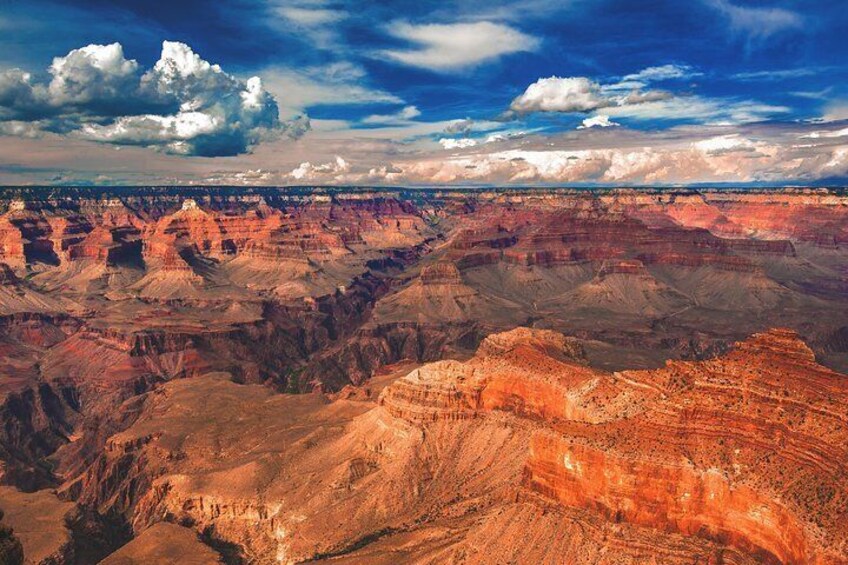 A vast canyon with layered rock formations and a bridge in the distance. 1
