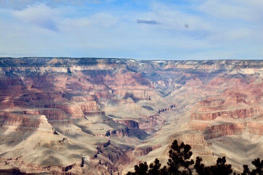 A vast canyon landscape with layered rock formations and sparse vegetation. 2