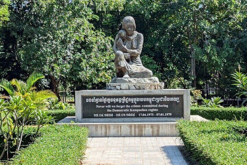 A statue of a seated figure with a plaque in a park. 3
