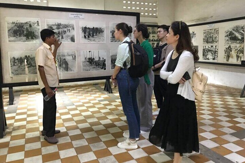 A group of people standing in front of a display with black and white photographs. 1
