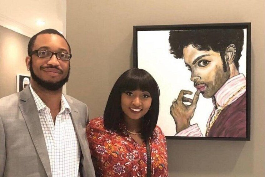 Dos personas de pie frente a una obra de arte enmarcada. 2