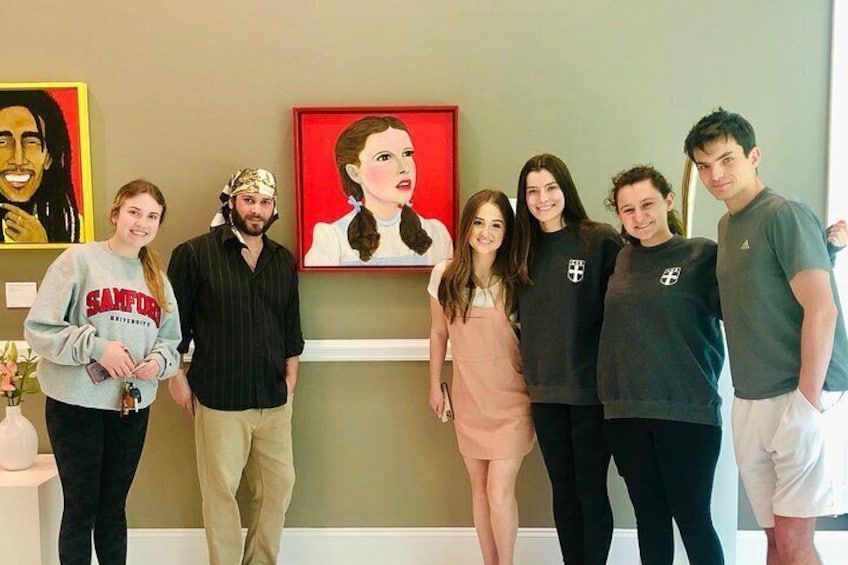 Un grupo de personas de pie en el interior, con un cuadro en la pared de fondo. 5