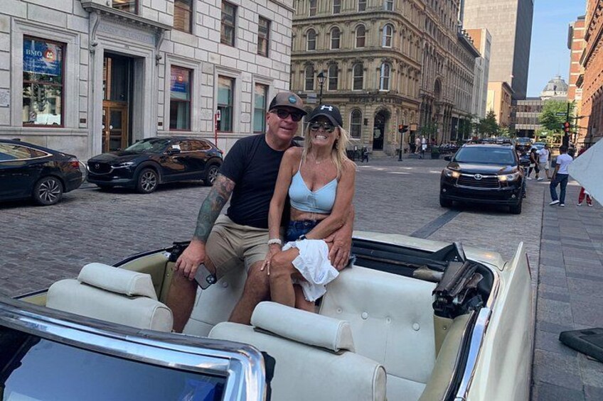 Ein Cabrio steht auf einer Stadtstraße, im Hintergrund sind Gebäude zu sehen. 3