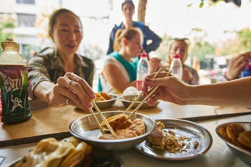 People eating at a table with chopsticks, a bottle, and a jar. 2