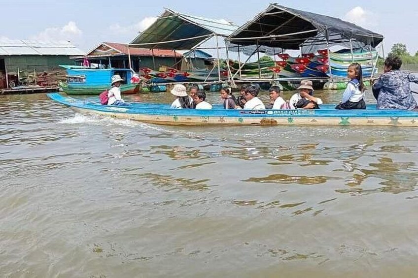 A group of people on a boat with a house-like structure in the background. 4