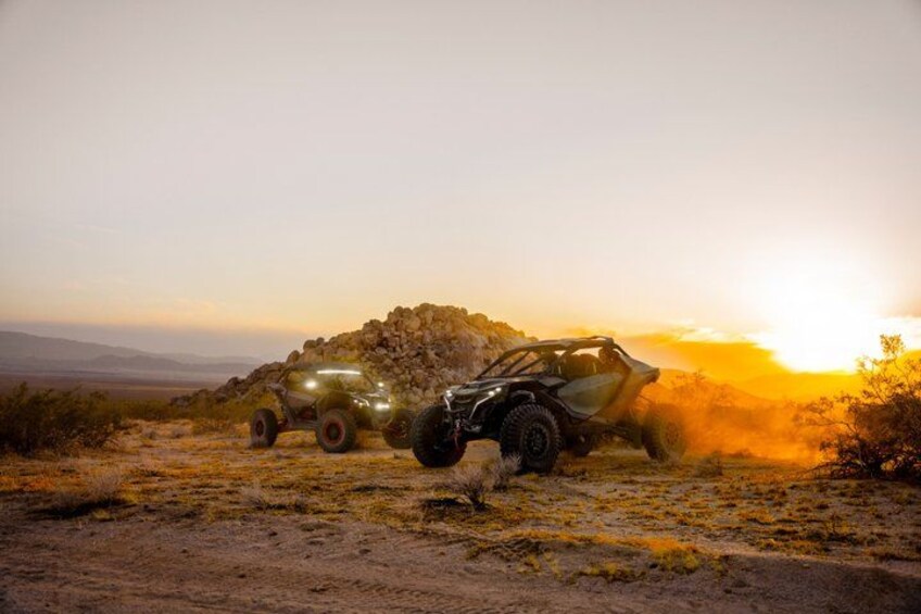 Off-road vehicles on a dirt path with a sunset in the background. 3