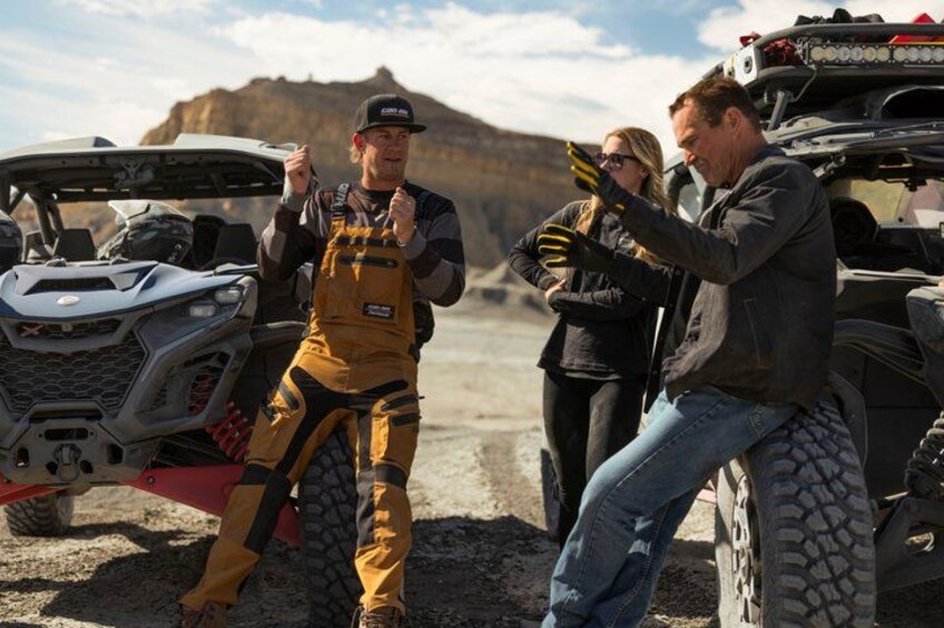A person in yellow overalls standing next to a quad bike, another person in a jacket, and a vehicle in the background. 5